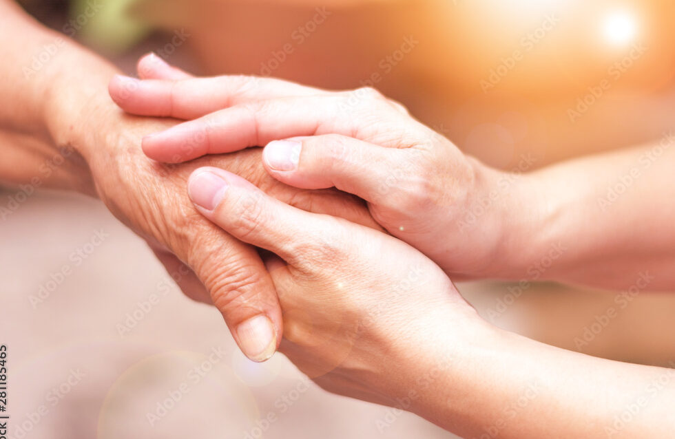 Caregiver, carer hand holding elder hand in hospice care. Philanthropy kindness to disabled concept.