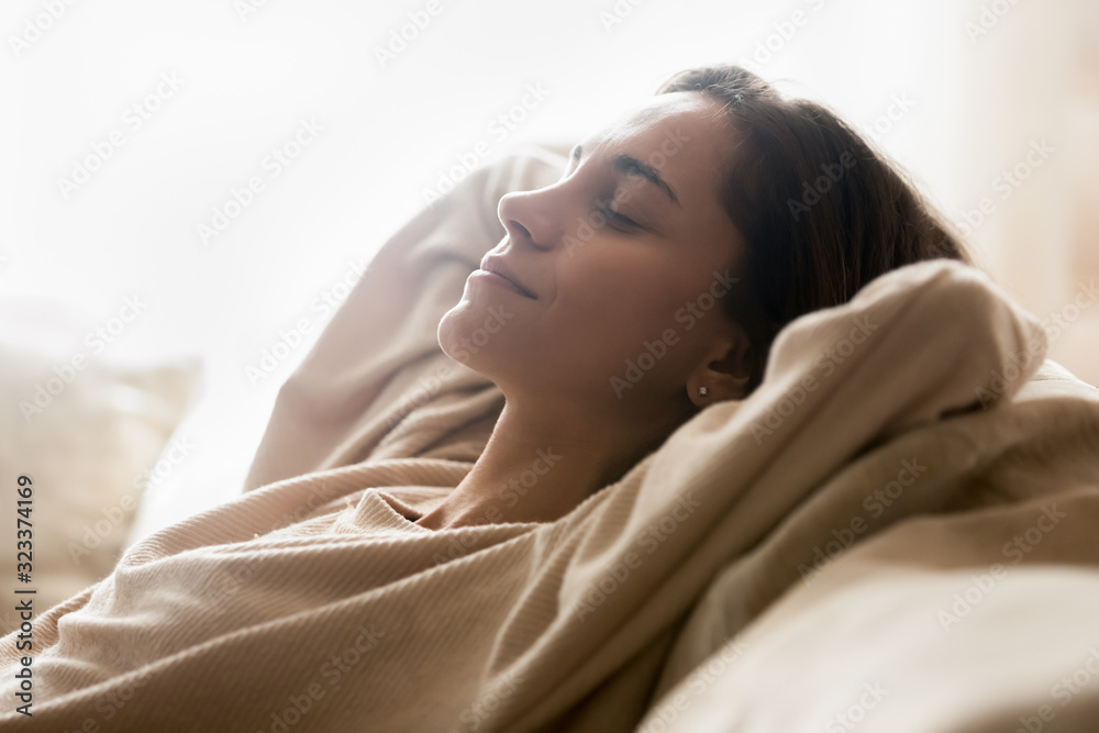 Happy young woman relaxing on comfortable sofa at home